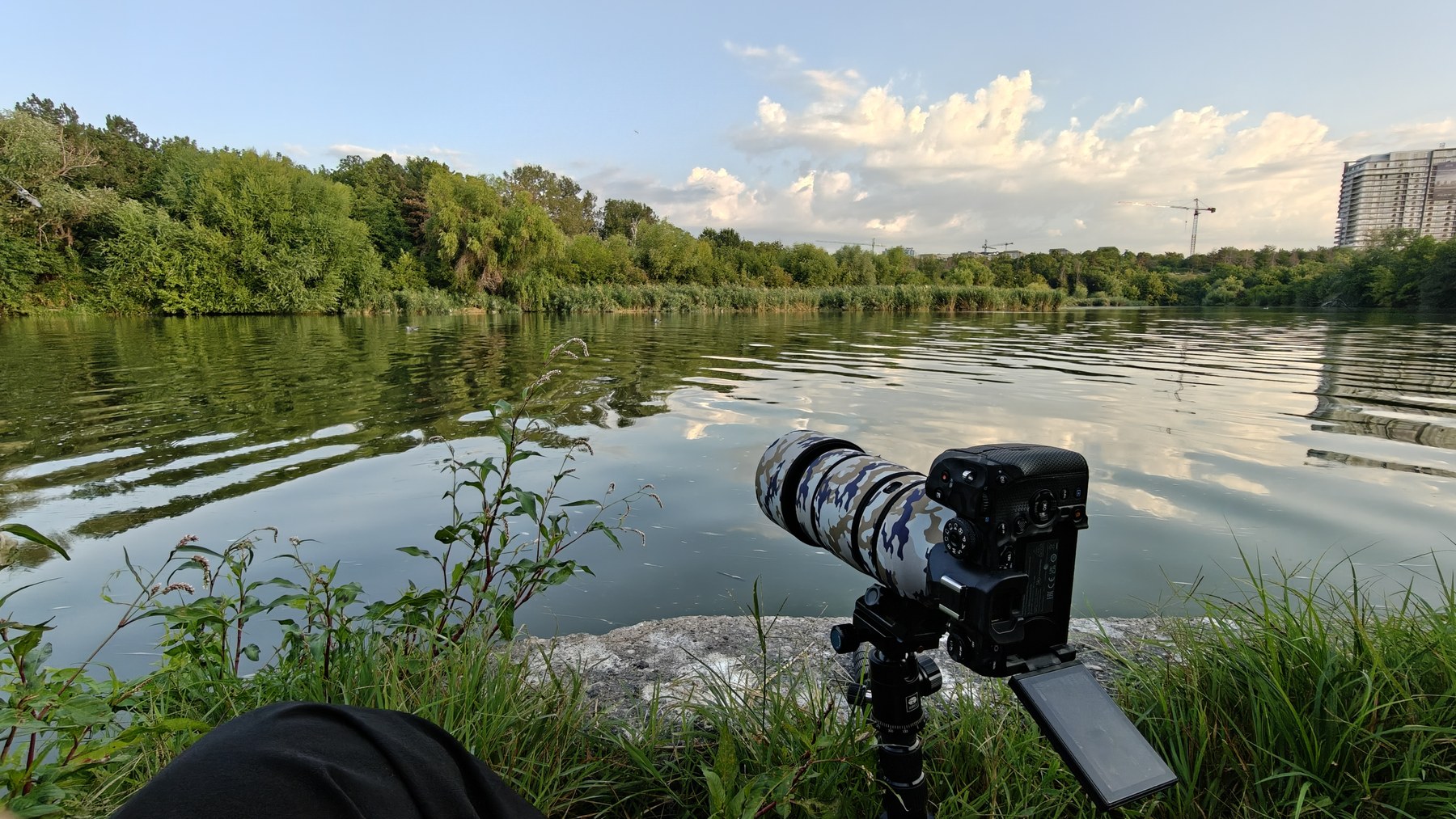 OM-1 camera with a long telephoto lens set beside the water